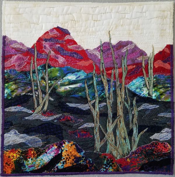 Dorothy Raymond - Wasteland - a landscape with distant mountains in red and purple. Some weeds grow in the foreground.